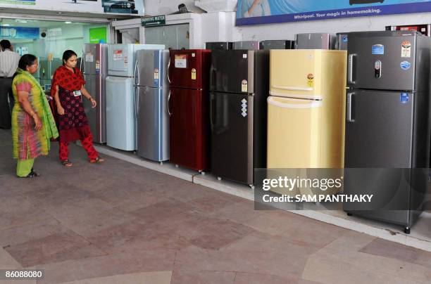Sales assistant shows an Indian prospective buyers refrigerators at Sales India on the eve of Earth Day in Ahmedabad on April 21, 2009. Earth Day on...