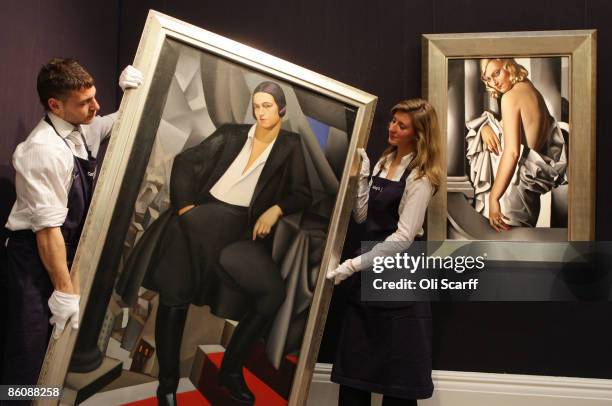 Gallery technicians at Sotheby's auction house lift a painting by Tamara de Lempicka entitled 'Portrait de la Duchesse de la Salle' from 1925, next...