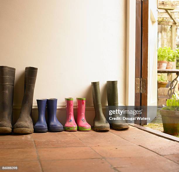 wellies lined up in hall way. - rubberlaars stockfoto's en -beelden