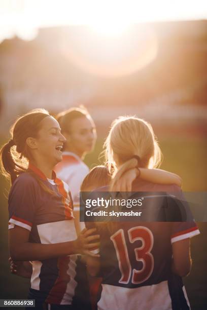 fröhliche teenager fußball-spieler lachend auf einem spielfeld bei sonnenuntergang. - sportbegriff stock-fotos und bilder