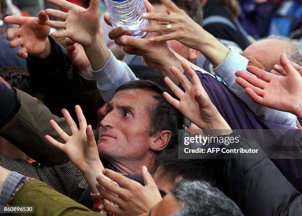 Hands of ethnic Albanian refugees reach out to get water after some thousand ethnic Albanians reached by foot Albania at the Albanian border...