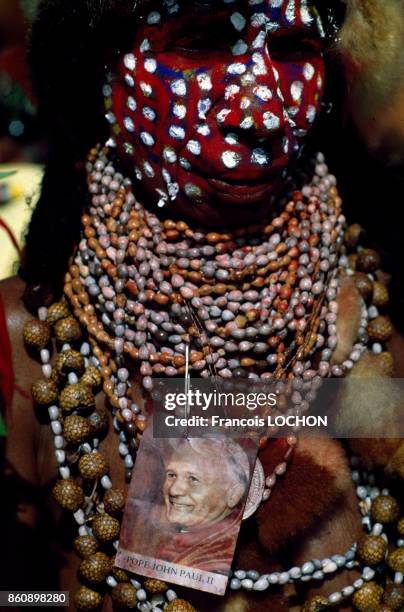 Une femme au visage peint et portant des colliers arbore une photo du pape Jean-Paul II en mai 1984 en Papouasie-Nouvelle-Guinée.