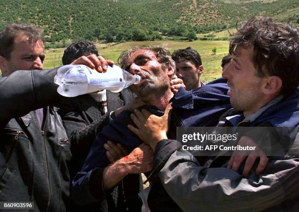 An exhausted Kosovo Albanian refugee is given water after reaching Albania at the checkpoint in Morina 05 June 1999. Around 100 men were released...