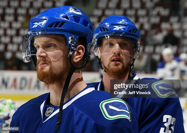 Twin bothers Daniel Sedin and Henrik Sedin of the Vancouver Canucks stand near the bench during Game Two of the Western Conference Quarterfinal Round...