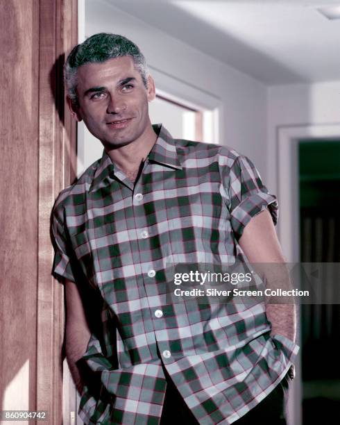 Portrait of American actor Jeff Chandler , hands in his pockets, as he leans in a doorway, 1950s.