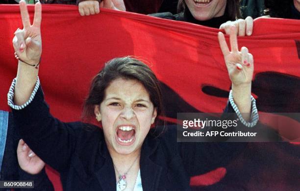 Young woman flashes the V-sign in front of the Albanian flag as some 10,000 people stage a demonstration in support of the Kosovo people and NATO air...