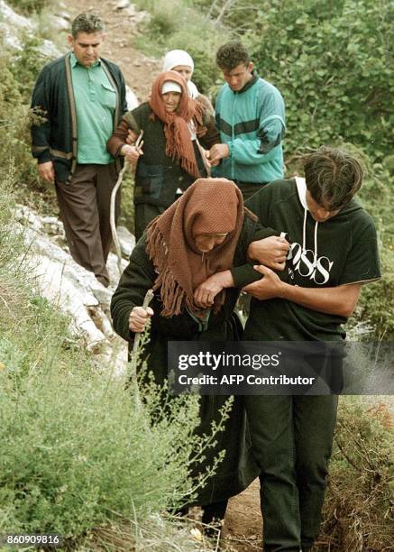 Local Albanian villagers help elderly ethnic Albanian refugees from the Morina village in Serbian province Kosovo to descend into the valley of...