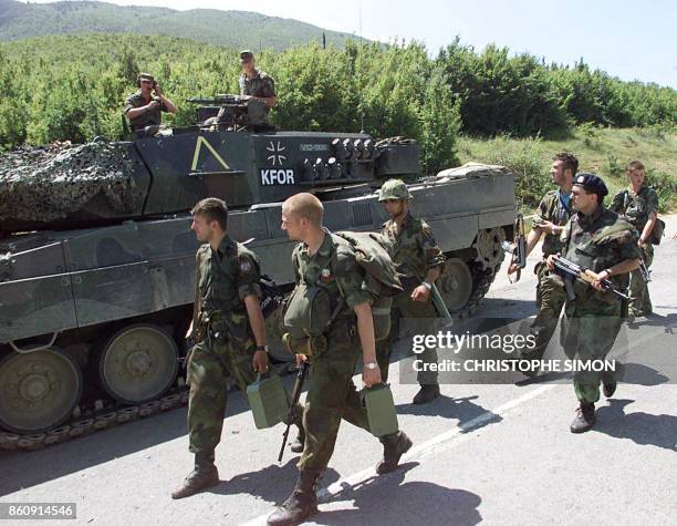 Serb soldiers withdrawing from the Morina border post walk 13 June 1999 a German tank part of the NATO-led KFOR troops in Morina. The 1,200-strong...