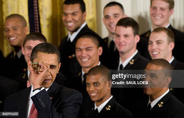 President Barack Obama looks through a replica championship ring given to him by the US Naval Academy football team as he presents the team with the...