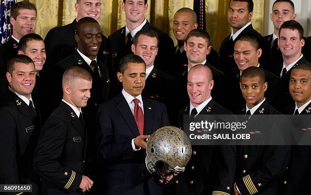 President Barack Obama looks at an autographed football helmet given to him by the US Naval Academy football team as he presents the team with the...