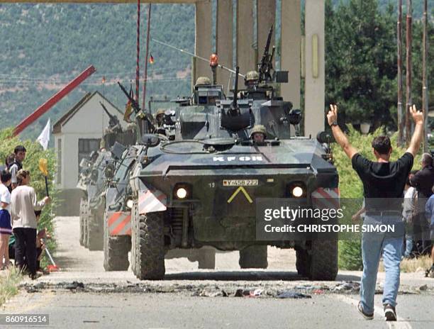 Ethnic Albanian refugees from Kosovo cheer 13 June as a convoy of German soldiers part of the NATO-led KFOR troops cross the Morina border post in...