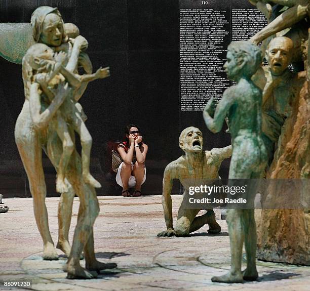 Inna Belogerkovskaya is overcome with emotion, as she pauses next to statues and lists of names of those killed, as she visits the Holocaust Memorial...