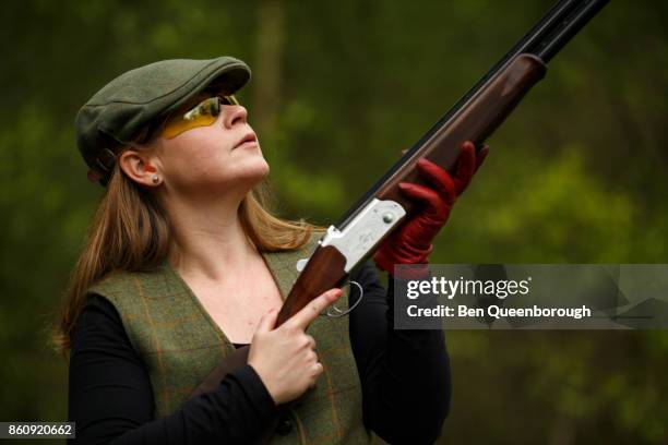 a woman aiming a rifle during at clay pigeon shoot - フラットキャップ ストックフォトと画像