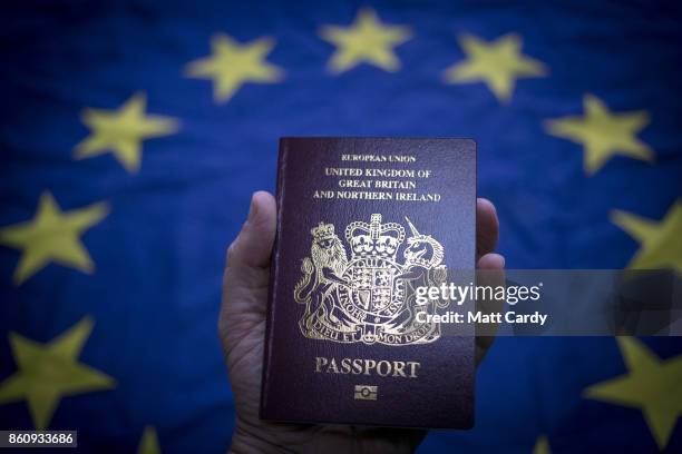 In this photo illustration, a man holds a British passport in front of the flag of the European Union on October 13, 2017 in Bath, England. Currency...