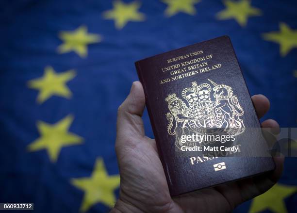 In this photo illustration, a man holds a British passport in front of the flag of the European Union on October 13, 2017 in Bath, England. Currency...
