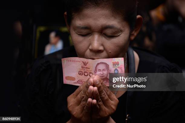 Thai mourner hold Thai baht the portrait of King Bhumibol Adulyadej at Siriraj Hospital where he died in Bangkok, Thailand, Friday, 13 October 2017....