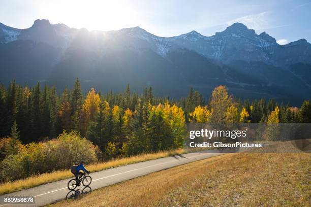 a male bike commuter rides the trans canada trail bike path near canmore, alberta, canada in the fall. - alberta stock pictures, royalty-free photos & images