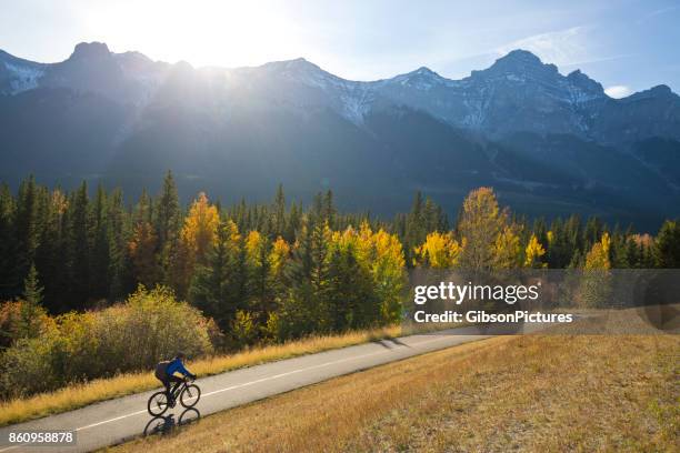 a male bike commuter rides the trans canada trail bike path near canmore, alberta, canada in the fall. - estrada trans canadá imagens e fotografias de stock