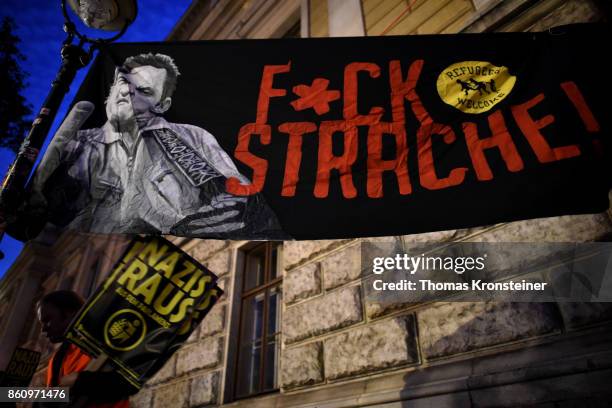 Demonstrator carries a sign reading 'Nazis get out' under a sign reading 'Fuck Strache!' during a protest on October 13, 2017 in Vienna, Austria....