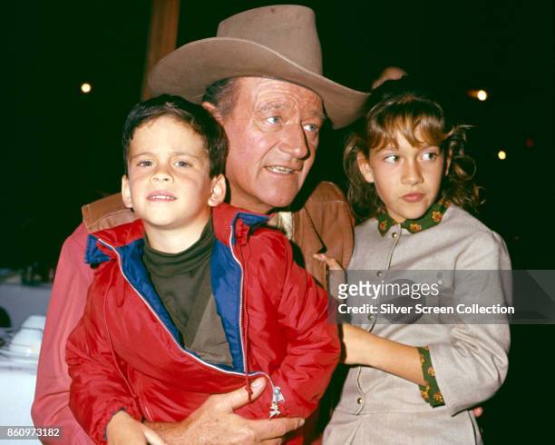 View of American actor John Wayne with two of his children, son John Ethan and daughter Aissa Wayne, as they are photographed in an unspecified...