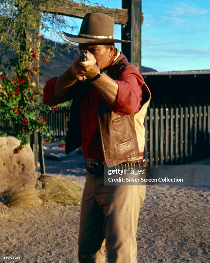 American actor John Wayne aims a rifle in a scene from 'El Dorado