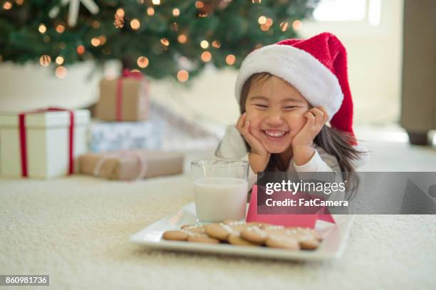 young girl in christmas hat puts out cookies and milk for santa - naughty santa stock pictures, royalty-free photos & images