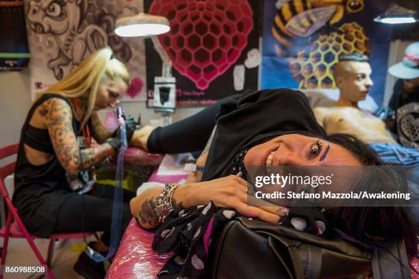 Tattooist at work on customers during the International Venice Festival Tattoo on October 13, 2017 in Venice, Italy.