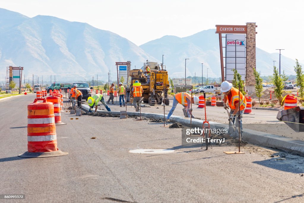 Several road construction workers smooth and clean up the center medium in a street that they laid in Spanish Fork, Utah