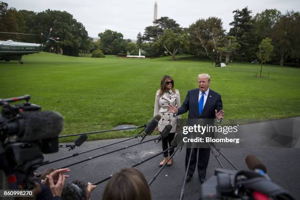 President Donald Trump, right, speaks to members of the media as First Lady Melania Trump stands before boarding Marine One on the South Lawn of the...