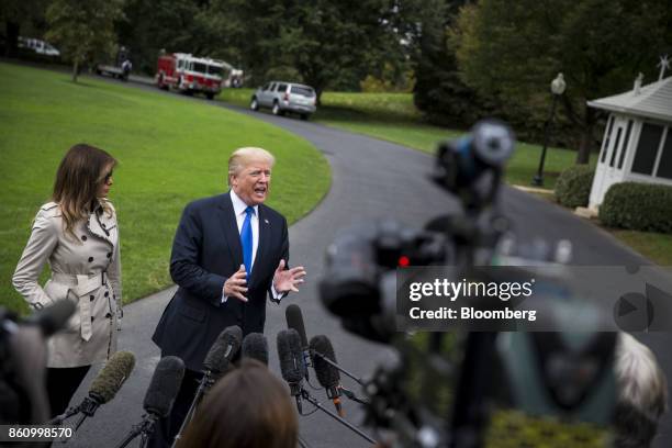 President Donald Trump, right, speaks to members of the media as First Lady Melania Trump stands before boarding Marine One on the South Lawn of the...