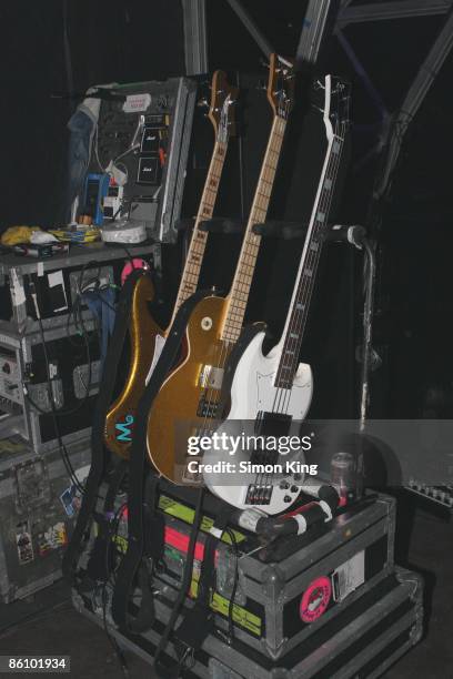 Photo of BASS GUITAR; three bass guitars on a stand backstage