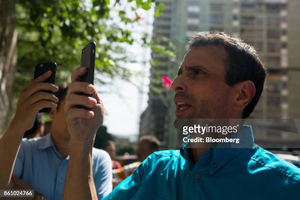 Henrique Capriles, opposition leader and former governor of the State of Miranda, right, uses a smartphone to live stream with periscope the changing...