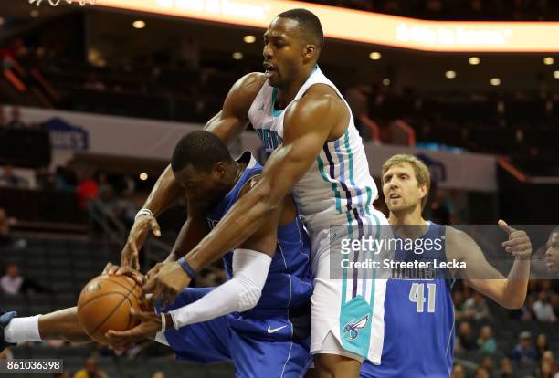 Dwight Howard of the Charlotte Hornets goes after a ball against Harrison Barnes as teammate Dirk Nowitzki of the Dallas Mavericks watches on during...
