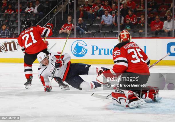 Kyle Palmieri of the New Jersey Devils trips up Nicklas Backstrom of the Washington Capitals during the first period as Cory Schneider watches at the...