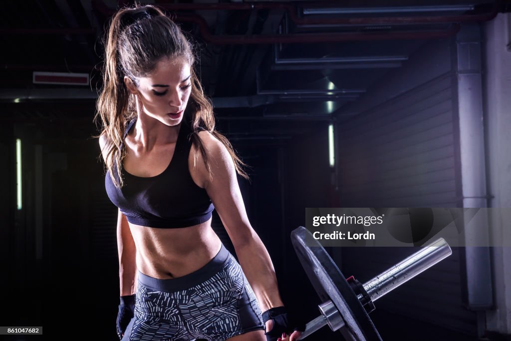 Attractive young fit sportswoman working out with weights