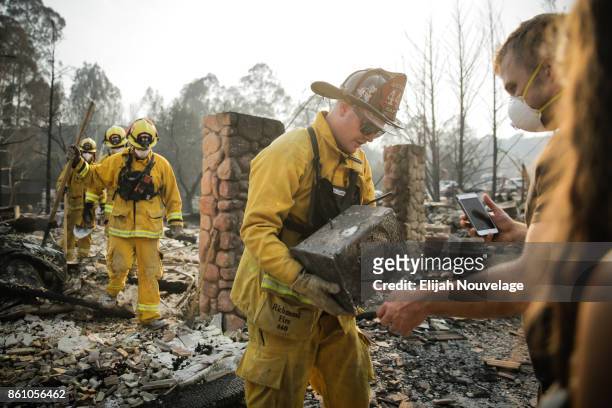Firefighter hands a safe to Julian and Lisa Corwin in the Fountaingrove neighborhood on October 13, 2017 in Santa Rosa, California. Corwin is part of...
