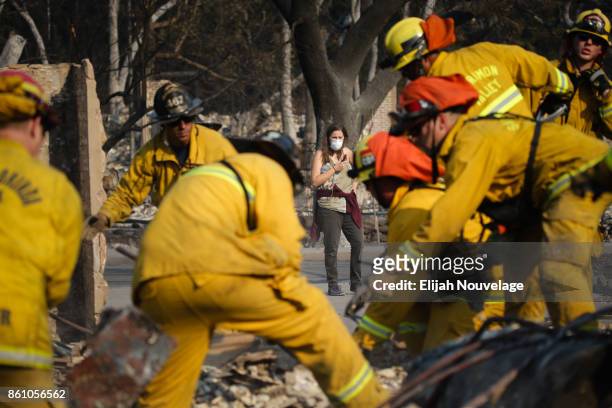 Lisa Corwin, center, watches as firefighters search for a strongbox and a wedding ring through the remains of a neighbor's home in the Fountaingrove...