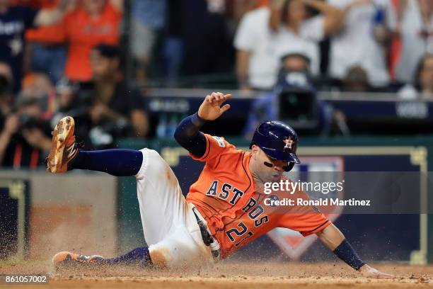 Jose Altuve of the Houston Astros slides into home to score on a single by Carlos Correa in the fourth inning against the New York Yankees during...