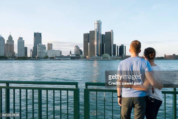junges paar blick auf skyline von detroit - detroit michigan stock-fotos und bilder