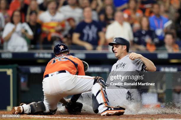 Greg Bird of the New York Yankees is tagged out at home by Brian McCann of the Houston Astros in the fifth inning during game one of the American...