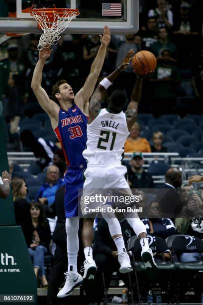 Tony Snell of the Milwaukee Bucks attempts a shot over Jon Leuer of the Detroit Pistons in the third quarter during a preseason game at BMO Harris...