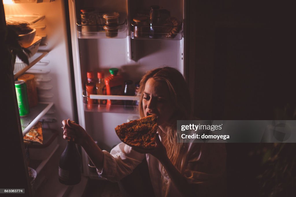 Junge Frau trinken und essen spät in die Nacht