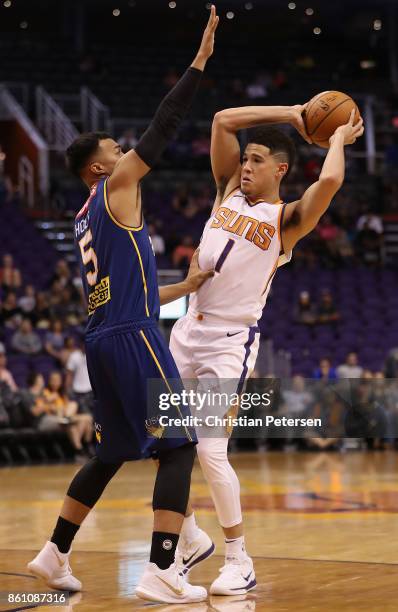 Devin Booker of the Phoenix Suns looks to pass around Stephen Holt of the Brisbane Bullets during the second half of the NBA preseason game at...