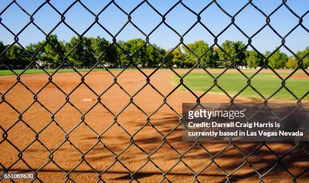 baseball field with fence in foreground - wire mesh fence stock-fotos und bilder