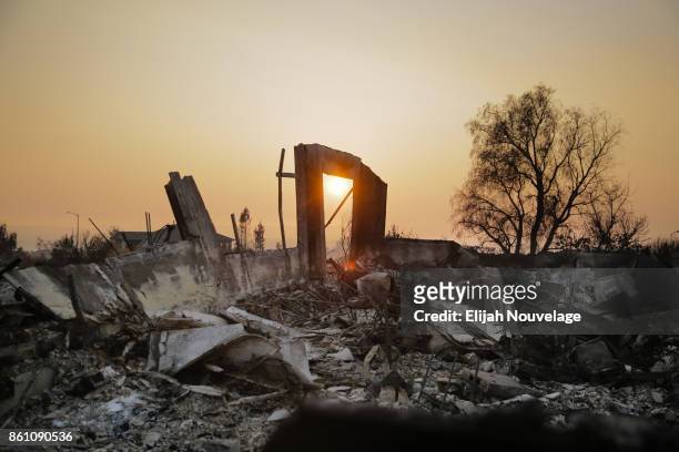 The sun sets through smoke over the remains of homes in the Fountaingrove neighborhood on Oct. 13, 2017 in Santa Rosa, California. Twenty four people...