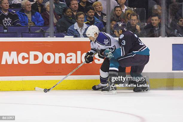 Right wing Steve Heinze of the Los Angeles Kings skates with the puck while being held by defenseman Jason York of the Anaheim Mighty Ducks during...