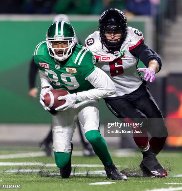 Duron Carter of the Saskatchewan Roughriders tries to run away from Antoine Pruneau of the Ottawa Redblacks after making a catch in the game between...