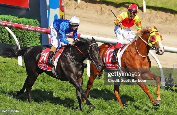 Jockey Michael Walker riding Mighty Boss celebrates as he wins race 8 the Ladbrokes Caulfield Guineas as jockey Damian Lane riding Kementari runs...