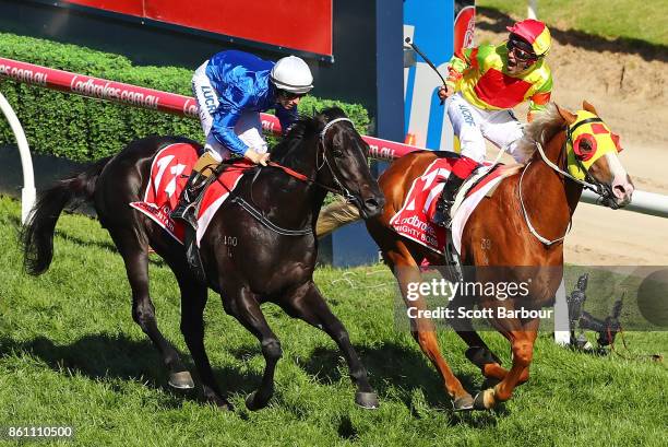 Jockey Michael Walker riding Mighty Boss celebrates as he wins race 8 the Ladbrokes Caulfield Guineas as jockey Damian Lane riding Kementari runs...