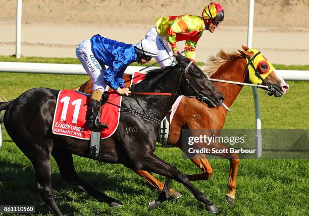 Jockey Michael Walker riding Mighty Boss celebrates as he wins race 8 the Ladbrokes Caulfield Guineas as jockey Damian Lane riding Kementari runs...